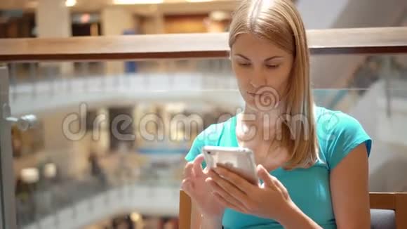 女人坐在购物中心广场上使用智能手机浏览看新闻和朋友聊天视频的预览图