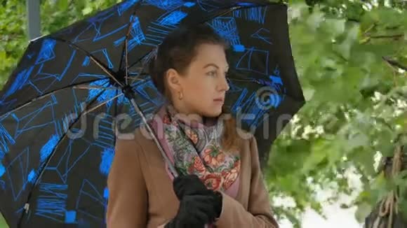 美丽的女孩躲在雨下的伞下视频的预览图