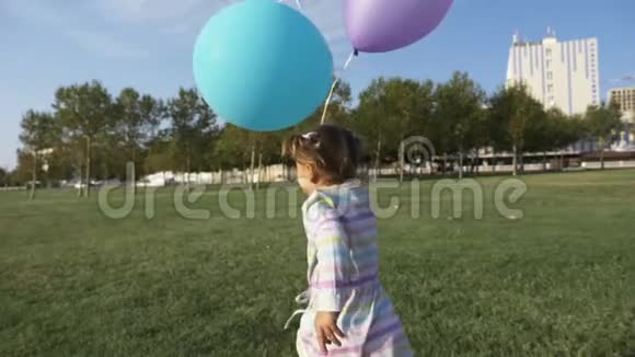 可爱的小女孩拿着气球在公园里跑笑着视频的预览图