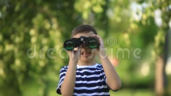 小男孩在公园里散步用望远镜看视频的预览图