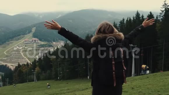 镜头跟随年轻女孩徒步旅行者在山上的风景举起手臂进入空中视频的预览图