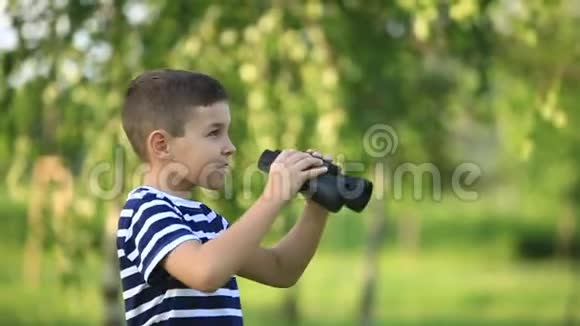 小男孩在公园里散步用望远镜看视频的预览图
