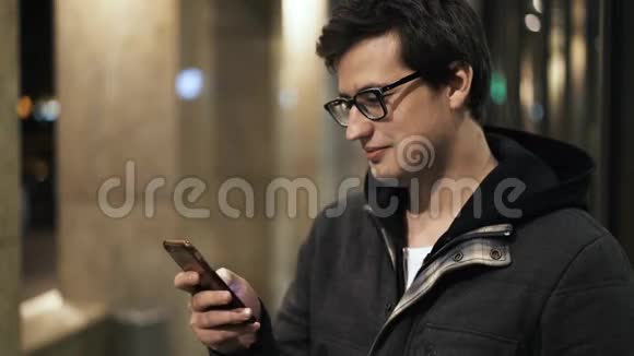 戴眼镜的年轻人在街边夜间发短信视频的预览图