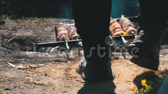 一个男人在乡下的一场大火上用烤肉串煮什什式烤肉串的腿的景色视频的预览图