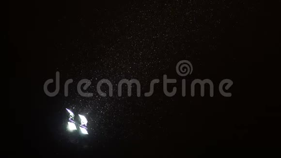雪正从夜空中的探照灯射进来视频的预览图