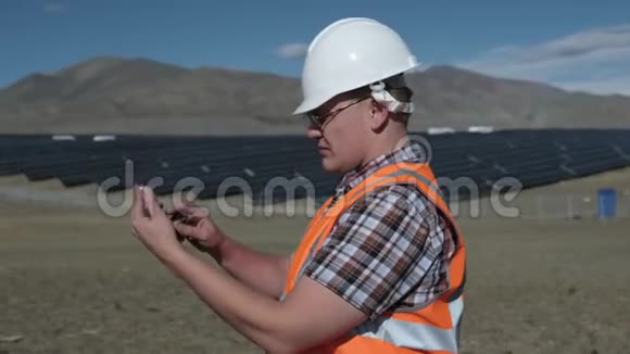 戴着头盔和背心的工程师在沙漠中的太阳能电池板项目上工作视频的预览图