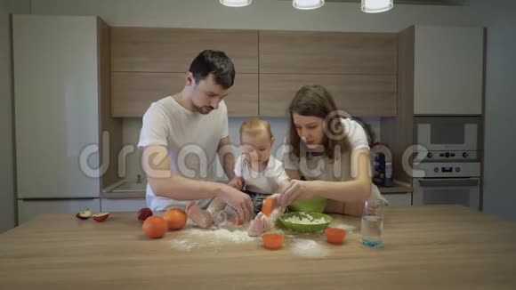 父母和一个小女儿一起在家里的厨房做饭家庭幸福的概念视频的预览图