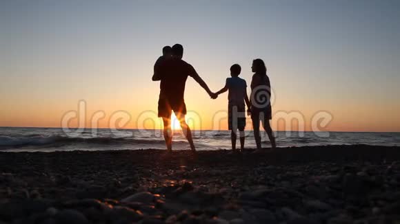 日落时海边的家庭剪影妈妈爸爸孩子们视频的预览图