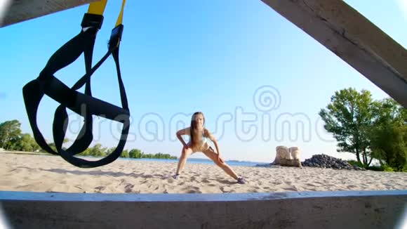 运动年轻女子穿着泳衣做拉伸平衡练习特写悬挂健身TRX系统TRX视频的预览图