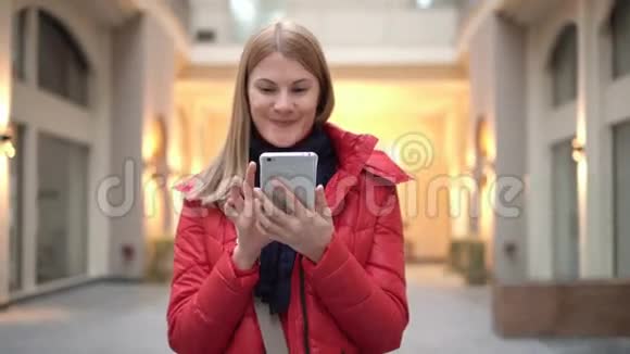 商场里有智能手机的漂亮女人通过电话交谈与她的朋友交流视频的预览图