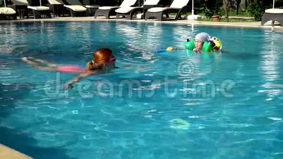 年轻的妈妈和她的小女儿在游泳池里游泳视频的预览图