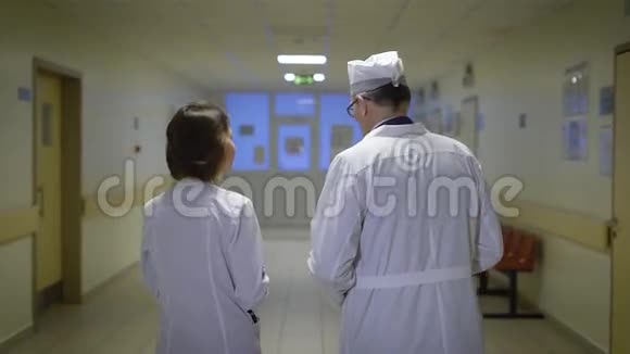 穿着实验室外套的男医生和女医生走在病房的走廊里与每个人交谈视频的预览图