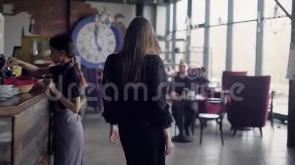 一个苗条的长发女人和她的男性朋友一起穿过咖啡馆走到桌子旁有人站起来了视频的预览图