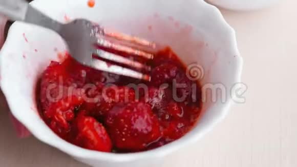 女人用叉子揉草莓把它和糖混在一起做果酱特写的手视频的预览图