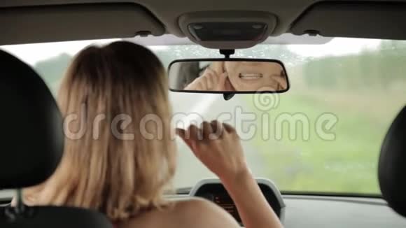 年轻的金发女人用牙线在她的车上的出租车上女人和牙线视频的预览图