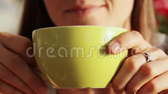 年轻漂亮的女人端着茶或咖啡坐着大口大口地喝着视频的预览图