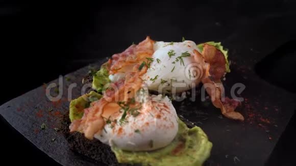 烤面包上有熏肉的蛋在黑色的石板上躺着视频的预览图