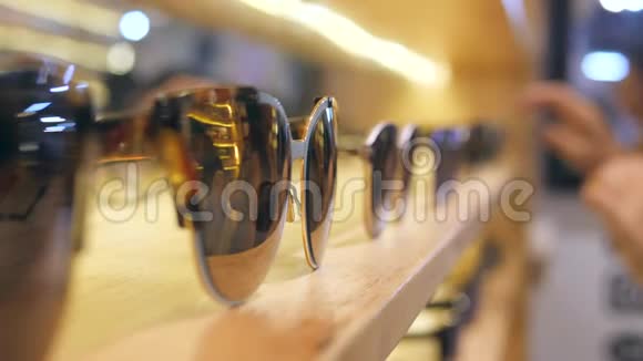 女顾客在商场货架上选购棕色镜片的太阳镜4K慢动作视频的预览图