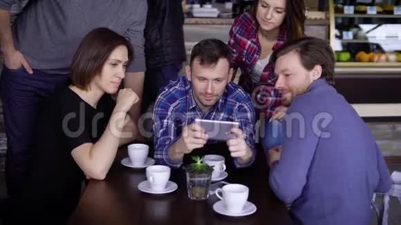 一群中年朋友在餐馆里的手机前笑个不停朋友在做联合活动视频的预览图
