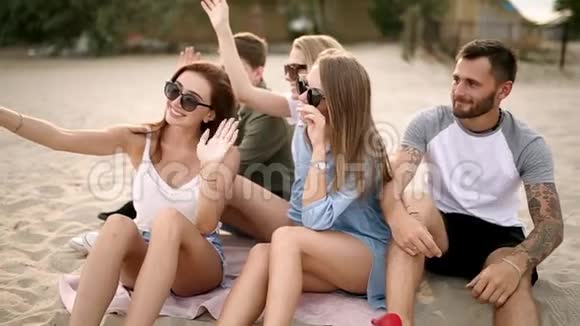 拍摄一群年轻朋友在海滩上自拍男人和女人坐在温暖的沙滩上拍照视频的预览图