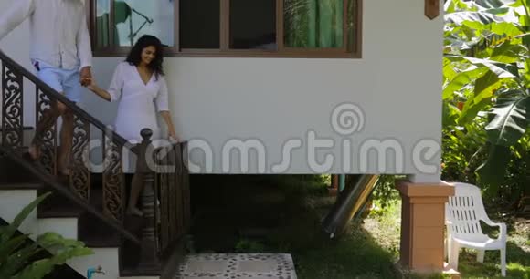 女主角在别墅附近的热带花园散步欢乐情侣在户外度假视频的预览图