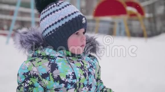 一个小孩在冬天的公园里玩雪孩子拿着铲子公园里有很多雪有趣的游戏视频的预览图