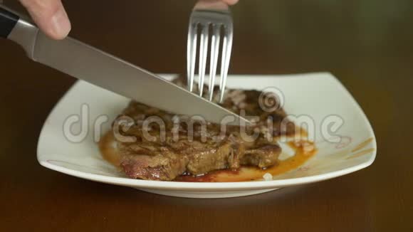关闭锁定的牛排手拿刀叉从盘子里拿出一部分肉牛排视频的预览图