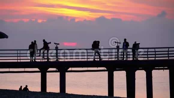 日落时海上码头上的人剪影视频的预览图