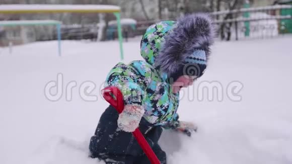一个小孩在冬天的公园里玩雪孩子拿着铲子公园里有很多雪有趣的游戏视频的预览图