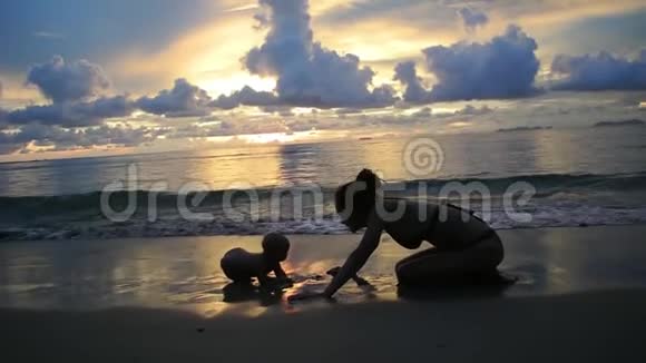 妈妈和宝宝正在日落时享受傍晚的大海视频的预览图