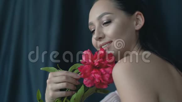 一个年轻的女人带着一堆牡丹在工作室里摆着相机慢动作视频的预览图