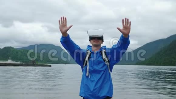 一个人在一个山湖的背景上使用虚拟现实眼镜视频的预览图