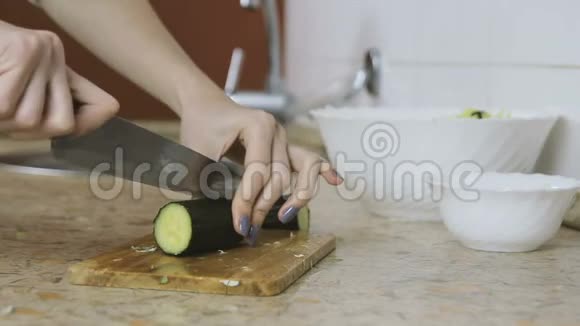 厨房餐桌上切黄瓜的女人手的特写从侧面看视频的预览图