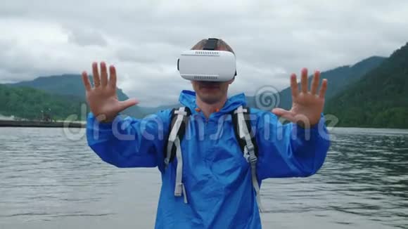 一个人在一个山湖的背景上使用虚拟现实眼镜视频的预览图