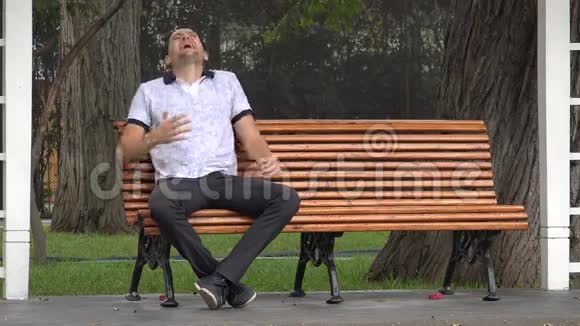 独自一人笑坐在公园的长椅上视频的预览图