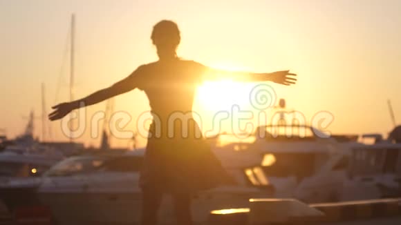 快乐的女人穿着裙子在舞蹈中旋转在日落的海船上跳跃游艇和镜头耀斑效应视频的预览图