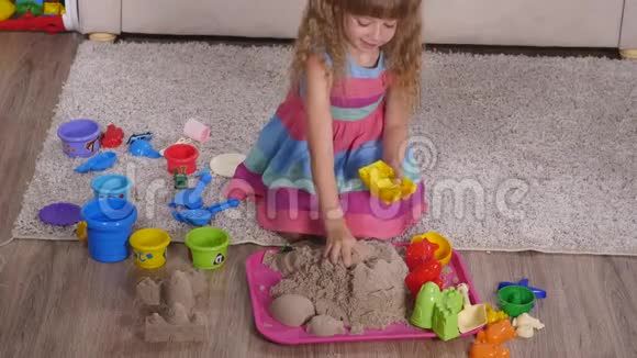 可爱的金发小女孩在工作室里玩沙子顶部视图视频的预览图
