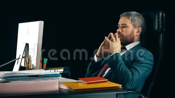 一个长胡子的商人在他的办公椅上摇摆黑色背景4K视频视频的预览图