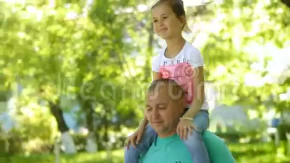 小女孩坐在男人脖子上他们正在公园里散步家庭视频的预览图