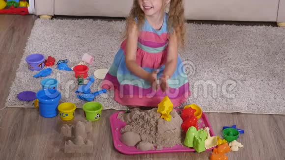 可爱的金发小女孩在工作室里玩沙子顶部视图视频的预览图