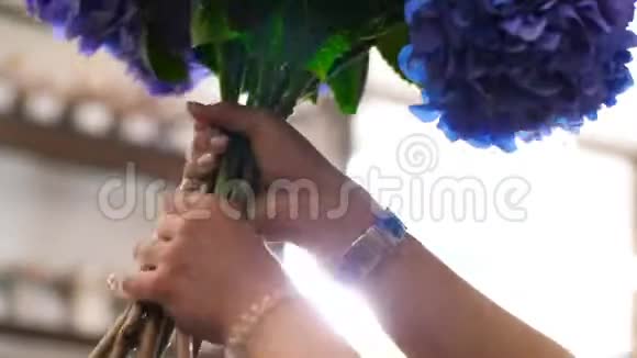 优雅的女性双手捻着一束奢华的蓝色花朵视频的预览图