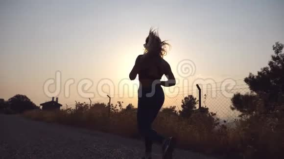 日出时在乡间小路上慢跑的运动女孩年轻女子早上在户外跑步健康活动视频的预览图
