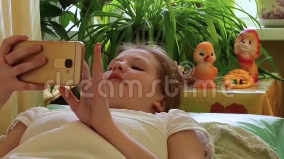 女孩躺在床上玩智能手机视频的预览图