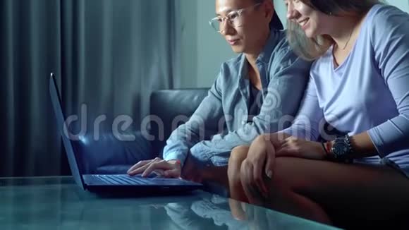 亚洲漂亮的年轻夫妇晚上坐在沙发上房间里有平板电脑视频的预览图