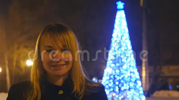 一个年轻的金发美女住在博克市圣诞树附近的一条冬夜街道上视频的预览图