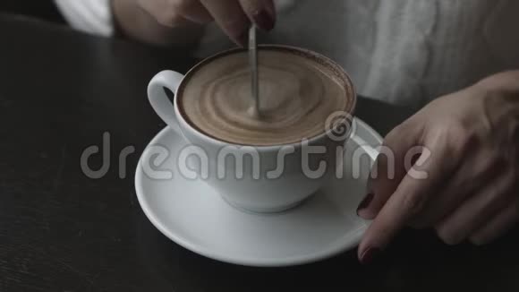 一个女孩坐在咖啡馆里喝茶咖啡加糖手里拿着一杯咖啡特写视频的预览图