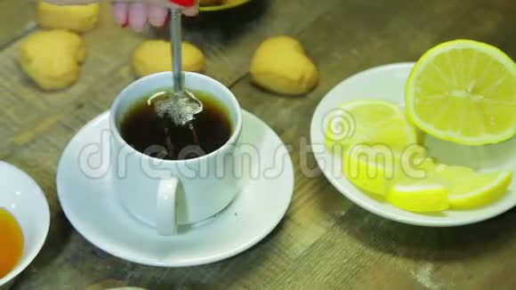 女人在木桌上的白色杯子里搅拌勺子鲜酿红茶视频的预览图