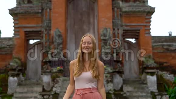 一名年轻女子在巴厘岛的塔曼阿云寺周围行走的慢镜头视频的预览图