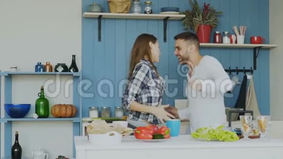 一对快乐而有魅力的年轻夫妇在爱中跳舞在家里的厨房里跳摇滚舞视频的预览图
