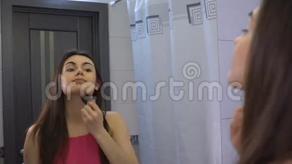 一个深色头发的女孩用刷子在脸上涂粉末视频的预览图